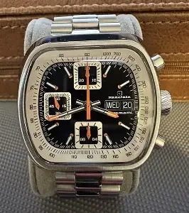 Close-up of a vintage wristwatch with a square face and metal band.
